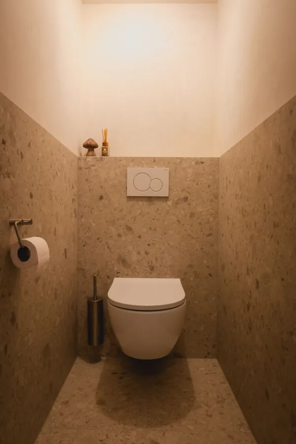 Toilet met hangend toilet en wandtegels in beige terrazzo, realisatie van ID Interieur