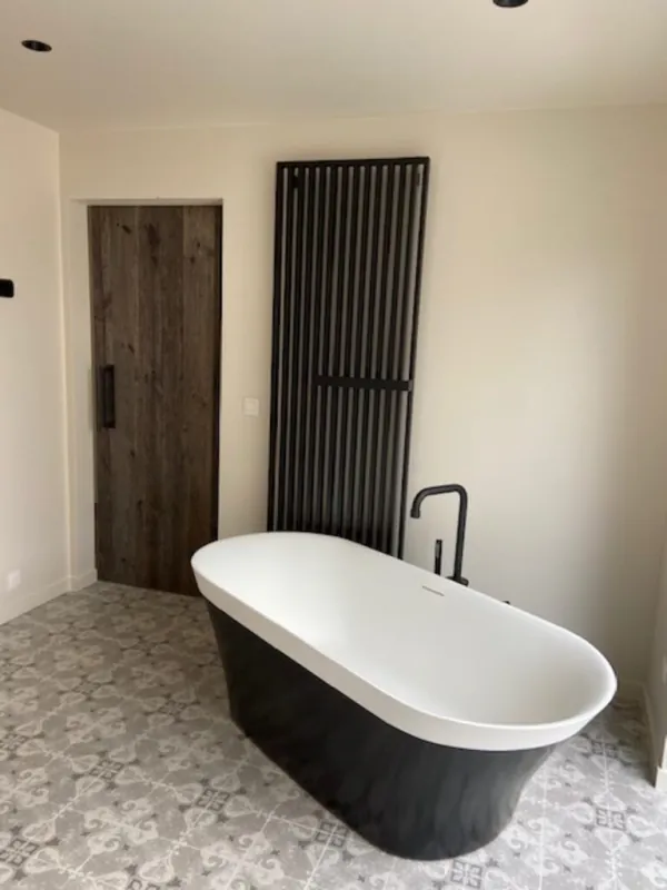 Vrijstaand zwart-wit bad met zwarte radiator en patroontegels, realisatie van ID Interieur