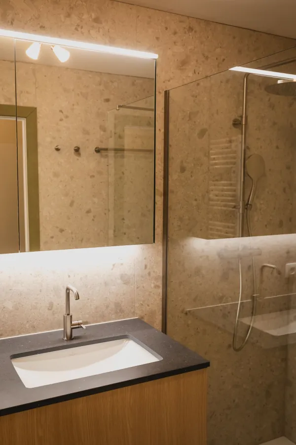 Inloopdouche met glazen wand en lavabo met verlichte spiegel, realisatie van ID Interieur