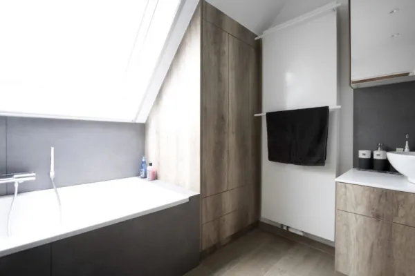 Bad onder een schuin dak met hoge kast in hout, realisatie van ID Interieur