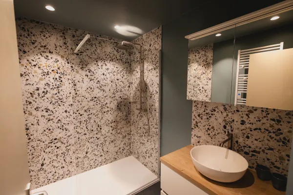 Badkamer in terrazzo met waskom op houten blad en spiegelkast, realisatie van ID Interieur