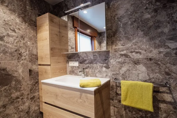 Badmeubel in eik met marmerlook wanden en hoge kolomkast, realisatie van ID Interieur
