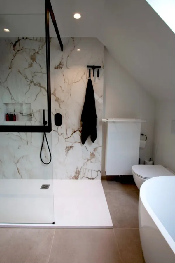 Badkamer onder het dak met marmerlook tegels en zwarte kranen, realisatie van ID Interieur