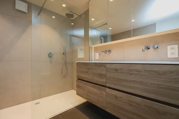 Badkamer met inloopdouche en lang houten badmeubel met twee kranen, realisatie van ID Interieur