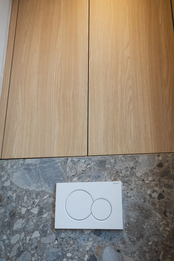 Ingebouwd toilet met bedieningsplaat en kast in hout erboven, realisatie van ID Interieur