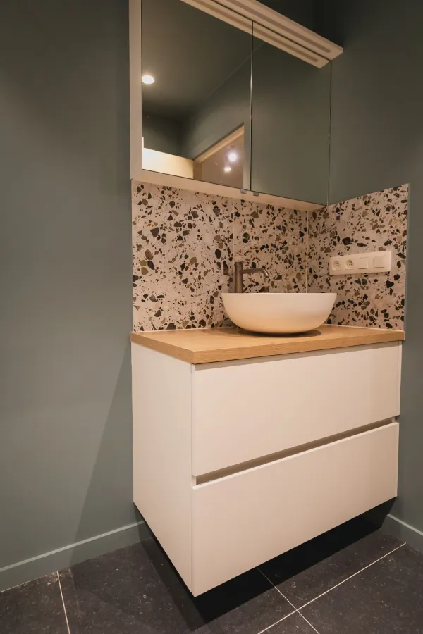 Waskom op wit badmeubel met terrazzo wand, realisatie van ID Interieur