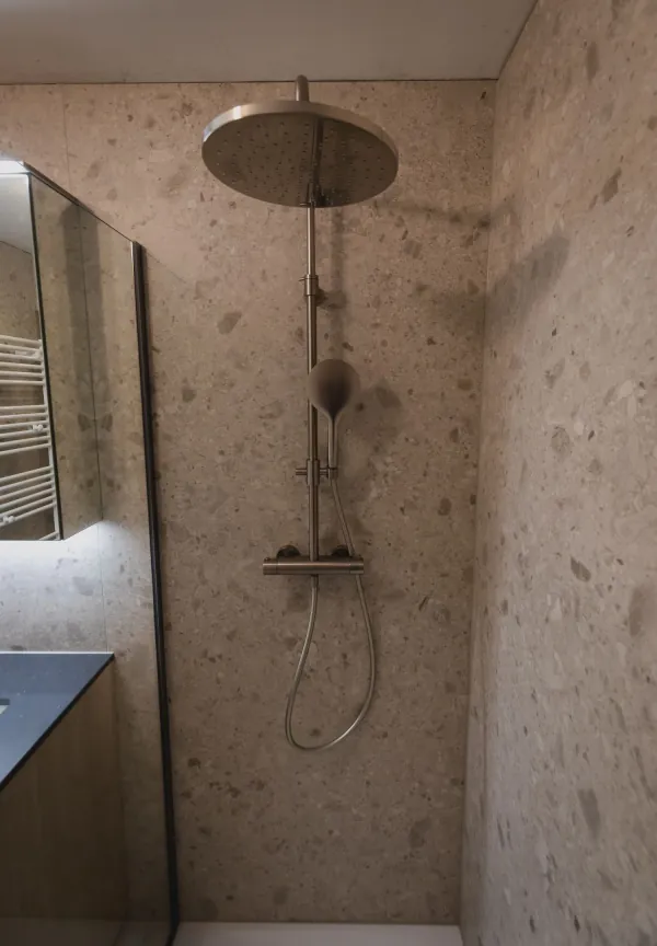 Douche met regendouche in terrazzo en glazen wand, realisatie van ID Interieur