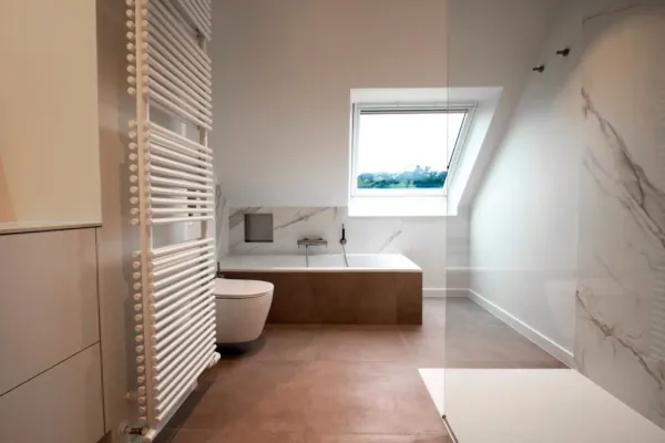 Badkamer onder het dakraam met ingebouwd bad en handdoekradiator, realisatie van ID Interieur