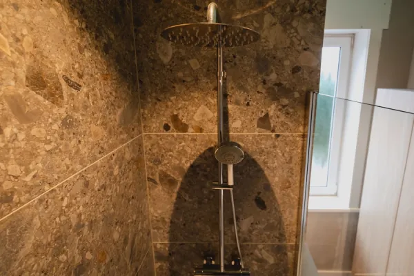 Inloopdouche met wanden in bruine terrazzo en regendouche, realisatie van ID Interieur