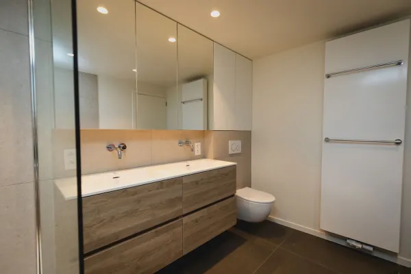 Badkamer met houten badmeubel, spiegelwand en hangend toilet, realisatie van ID Interieur