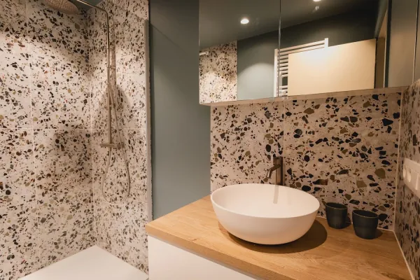 Badkamer in terrazzo met waskom op eiken blad, realisatie van ID Interieur