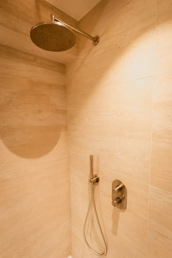 Inloopdouche met beige houtlooktegels en bronzen douchekraan, realisatie van ID Interieur
