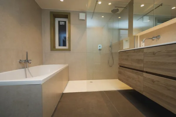 Badkamer met ingebouwd bad, inloopdouche en houten badmeubel, realisatie van ID Interieur