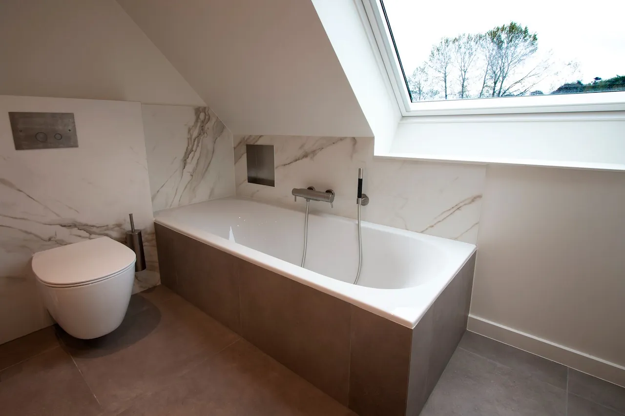 Bad onder het dakraam met hangend toilet en marmerlook wanden, Badkamerrenovatie Baarlevelde door ID Interieur