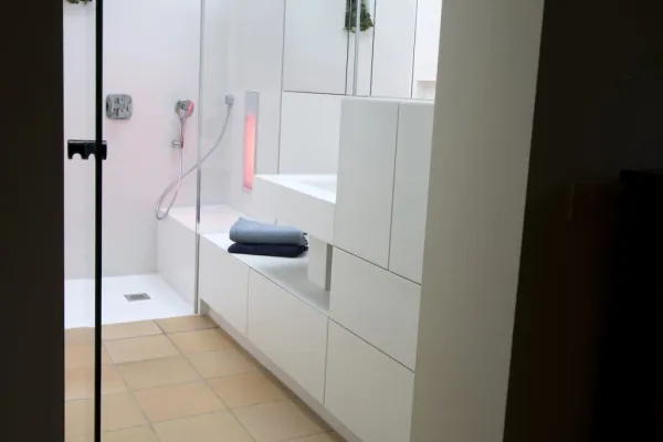 Witte kasten op maat naast een inloopdouche, realisatie van ID Interieur