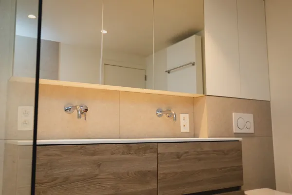 Lang badmeubel in hout met twee inbouwkranen en spiegelkast, realisatie van ID Interieur
