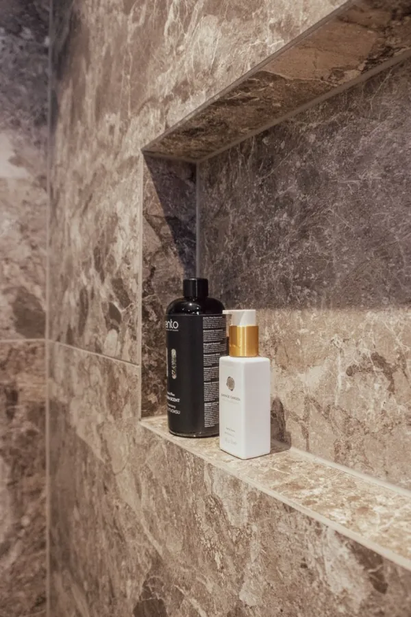 Ingewerkte nis in een douche met bruine natuursteentegels, realisatie van ID Interieur