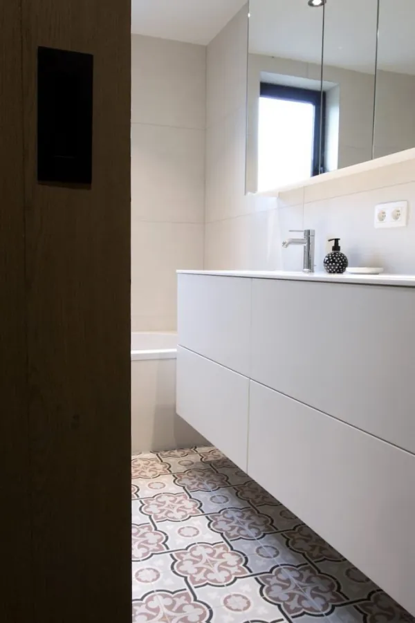 Wit zwevend badmeubel met vloer in cementtegels, realisatie van ID Interieur