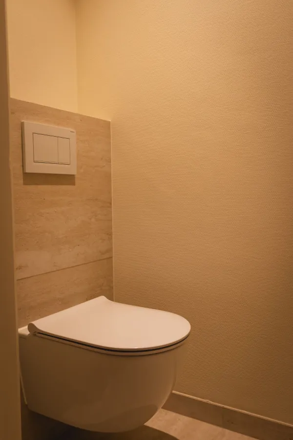 Hangend toilet tegen beige wandtegels, realisatie van ID Interieur