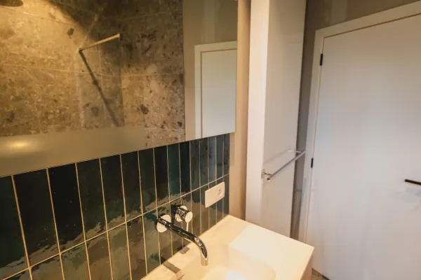 Groene wandtegels en kraan boven een lavabo, realisatie van ID Interieur