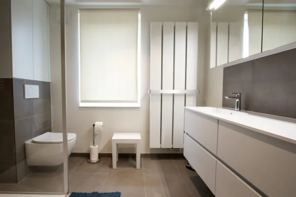 Badkamer met wit badmeubel, hangend toilet en designradiator, realisatie van ID Interieur
