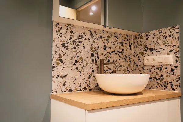 Waskom op houten blad tegen een wand in terrazzo, realisatie van ID Interieur