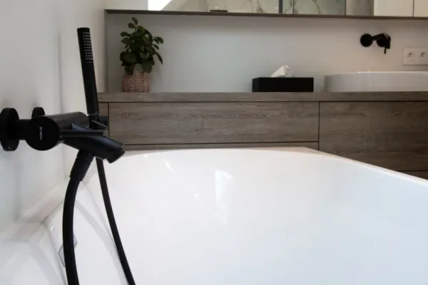 Bad met zwarte badkraan voor een houten badmeubel, realisatie van ID Interieur