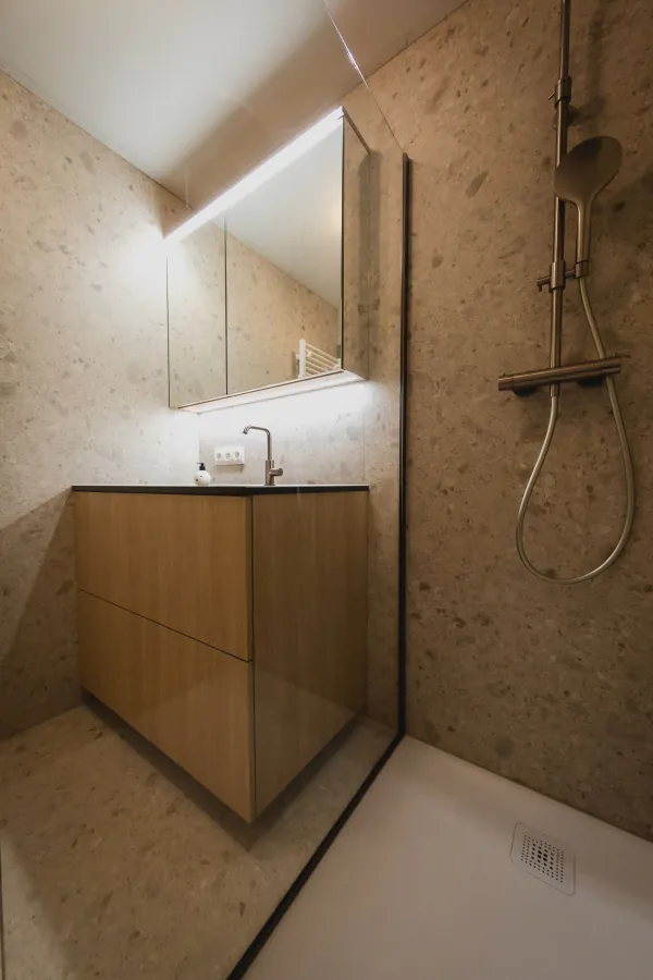 Douche in terrazzo met houten badmeubel ernaast, realisatie van ID Interieur