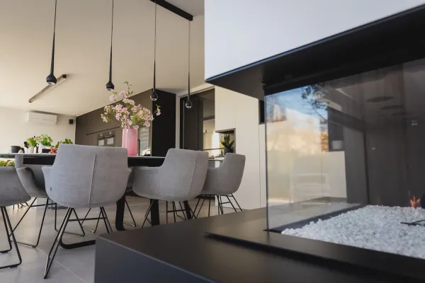 Eetplaats met hanglampen naast een glazen gashaard, realisatie van ID Interieur