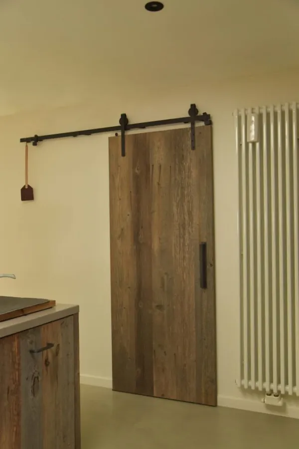 Schuifdeur in oud hout met zwarte rail, realisatie van ID Interieur