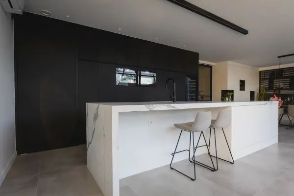 Keuken met marmeren kookeiland, barkrukken en zwarte kastenwand, realisatie van ID Interieur