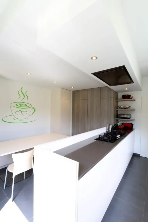 Witte keuken met lange werkbank en verlaagd plafond, realisatie van ID Interieur