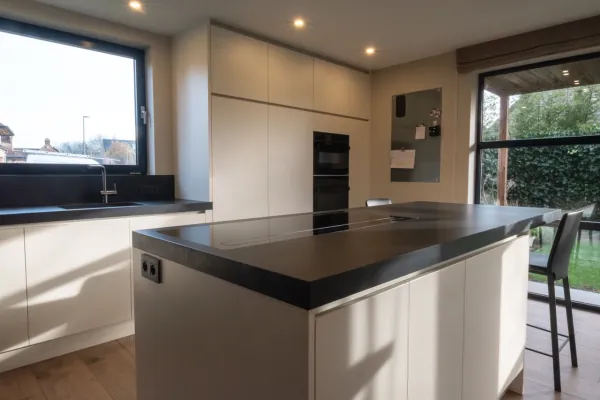 Keuken met donker eiland, witte kasten en grote ramen, realisatie van ID Interieur