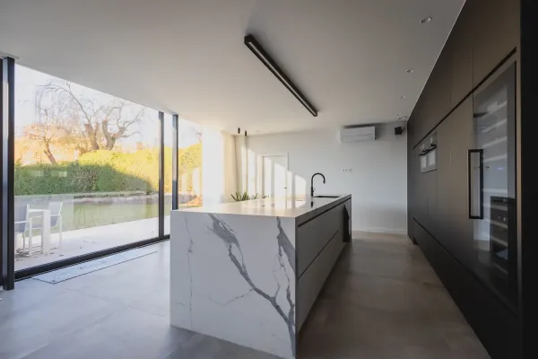 Zwarte kastenwand en wit marmerlook eiland in een open keuken, realisatie van ID Interieur