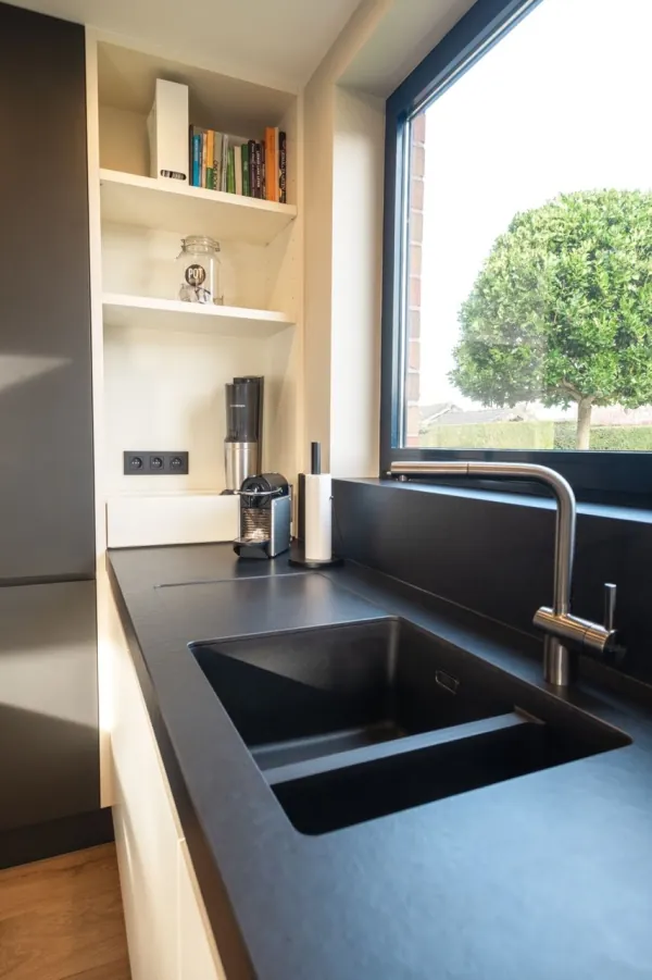 Keukenhoek met zwart werkblad, spoelbak en open rekken, realisatie van ID Interieur