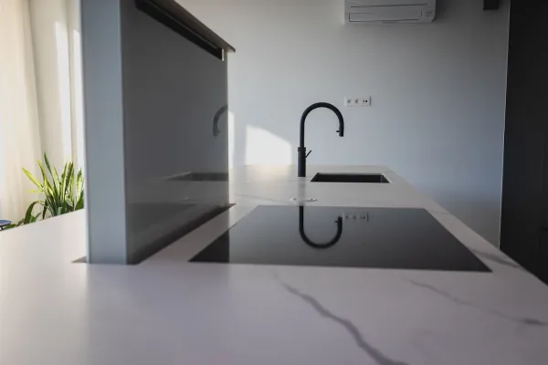 Kookeiland met wit werkblad en zwarte kraan, realisatie van ID Interieur