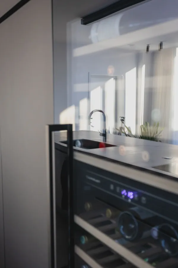 Wijnkoelkast ingebouwd in een donkere keuken, realisatie van ID Interieur