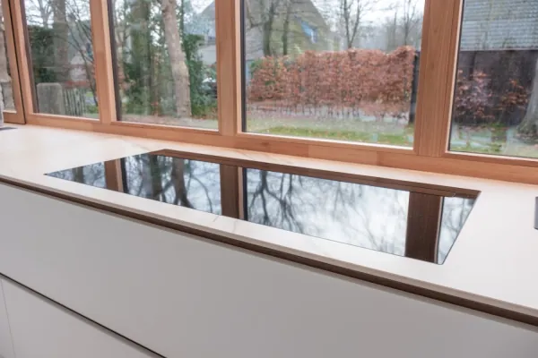 Kookplaat in een wit werkblad voor een raampartij, realisatie van ID Interieur