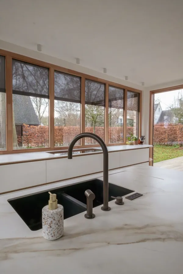 Spoelbak met bronzen kraan op een marmerlook werkblad, realisatie van ID Interieur