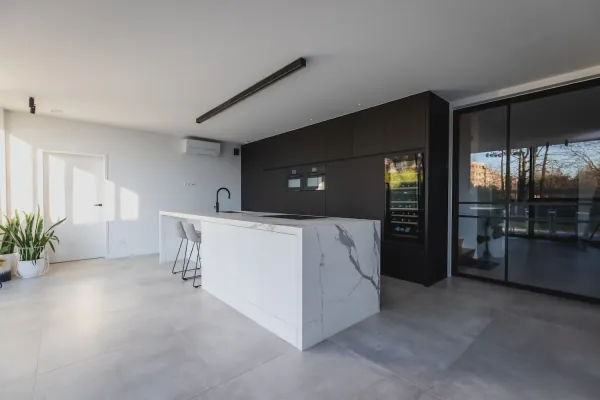Open keuken met marmerlook eiland en zwarte kastenwand, realisatie van ID Interieur