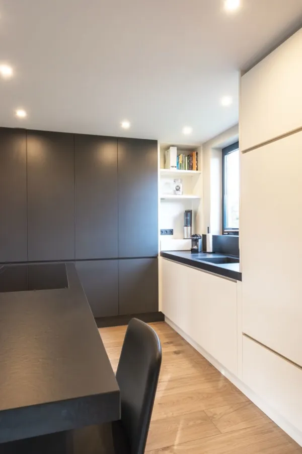 Keuken met donkere en witte kasten en eettafel, realisatie van ID Interieur