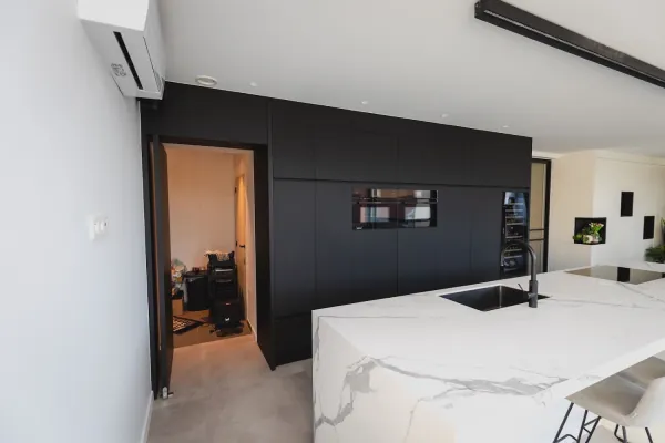 Keuken met marmerlook eiland en zwarte kastenwand met deur, realisatie van ID Interieur