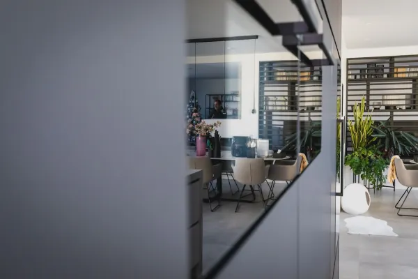 Zwarte kastenwand met glazen doorkijk naar de leefruimte, realisatie van ID Interieur