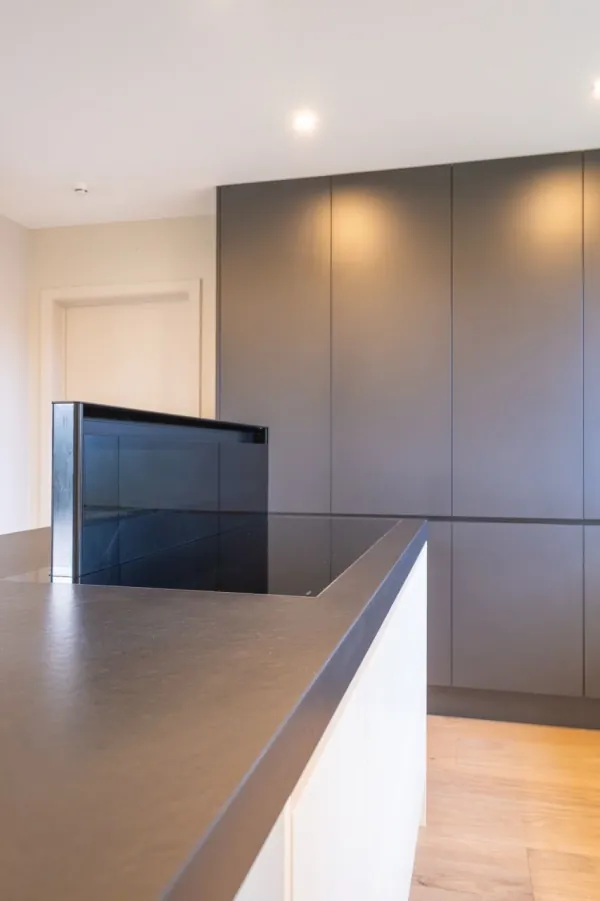 Keukeneiland met donker werkblad en grijze kasten, realisatie van ID Interieur