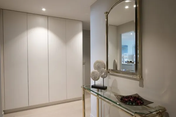 Witte kastenwand zonder grepen in een inkom, realisatie van ID Interieur