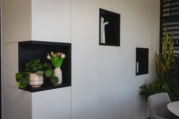 Witte kastenwand met zwarte nissen en plantjes, realisatie van ID Interieur