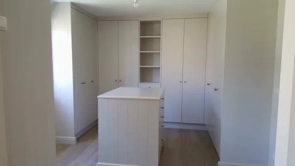 Witte inbouwkasten met open rek rond een eiland, realisatie van ID Interieur