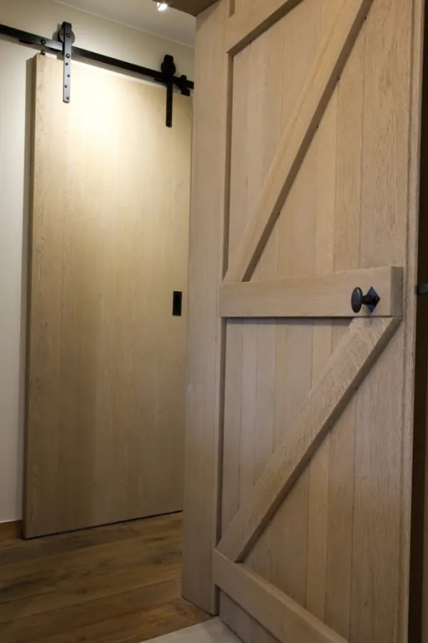 Schuifdeur in eikenhout met zwart beslag, realisatie van ID Interieur