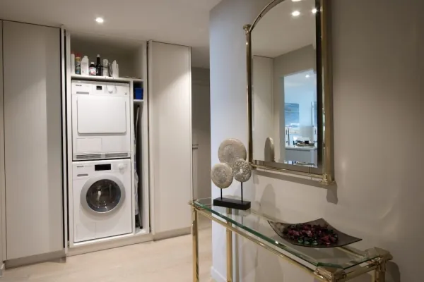 Witte kastenwand met wasmachine en droogkast ingebouwd, realisatie van ID Interieur