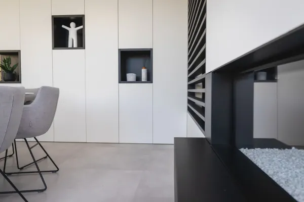 Witte kastenwand met nissen en zwarte gashaardombouw, realisatie van ID Interieur